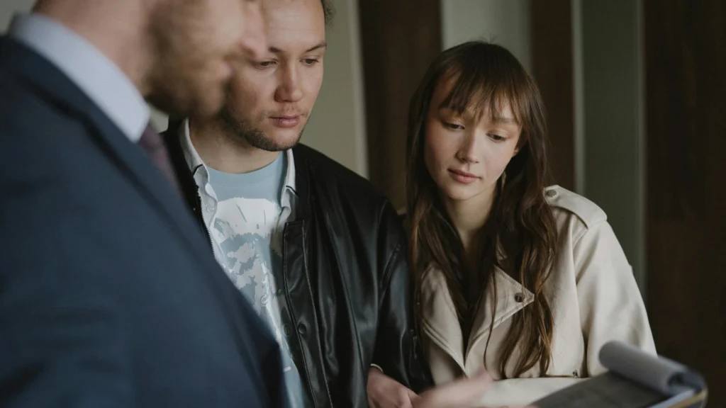 Couple reviewing documents with a professional, discussing paperwork and business or legal details
