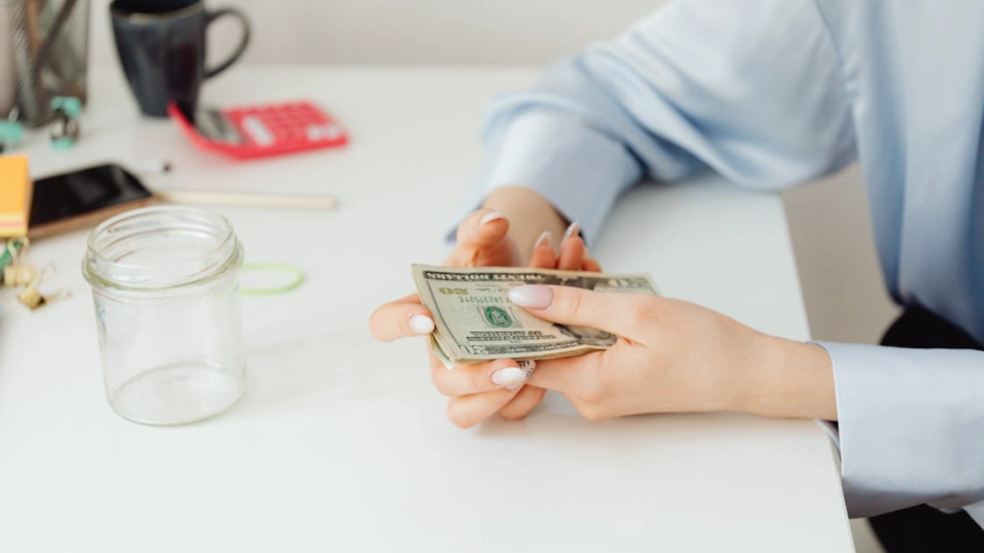 Person counting cash at desk to illustrate HVAC business owner salary and profits