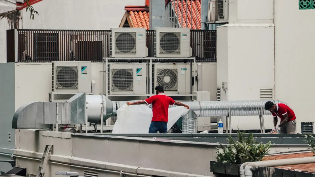 HVAC technicians working on rooftop commercial air conditioning units and ductwork
