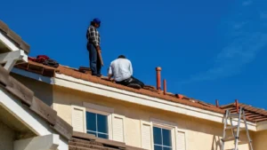 Roofers installing shingles on residential home roof under clear blue sky