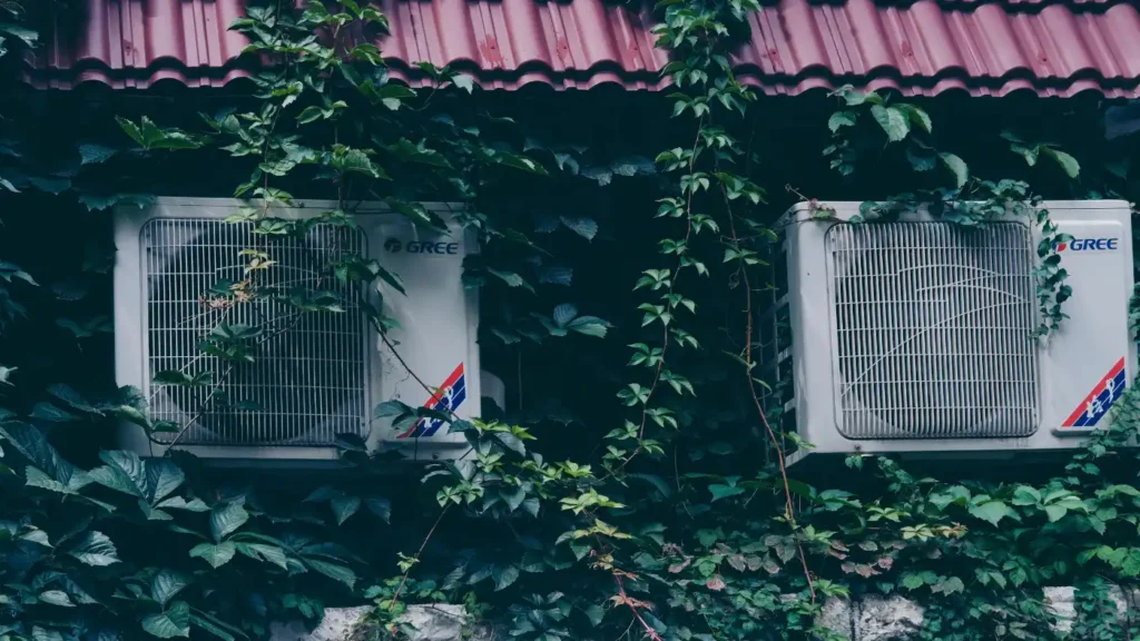 HVAC outdoor units mounted on building exterior surrounded by greenery