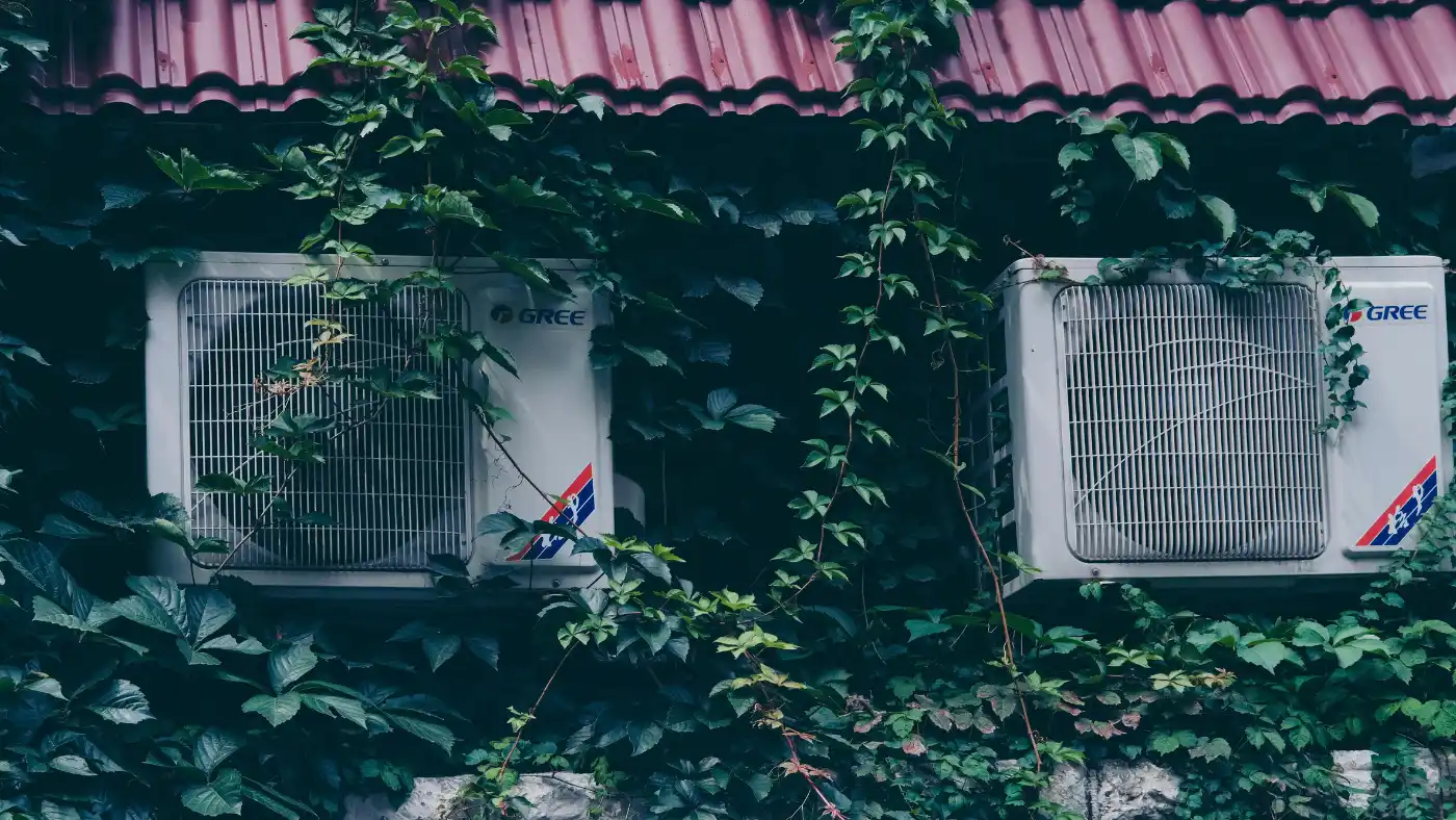 HVAC outdoor units mounted on building exterior surrounded by greenery