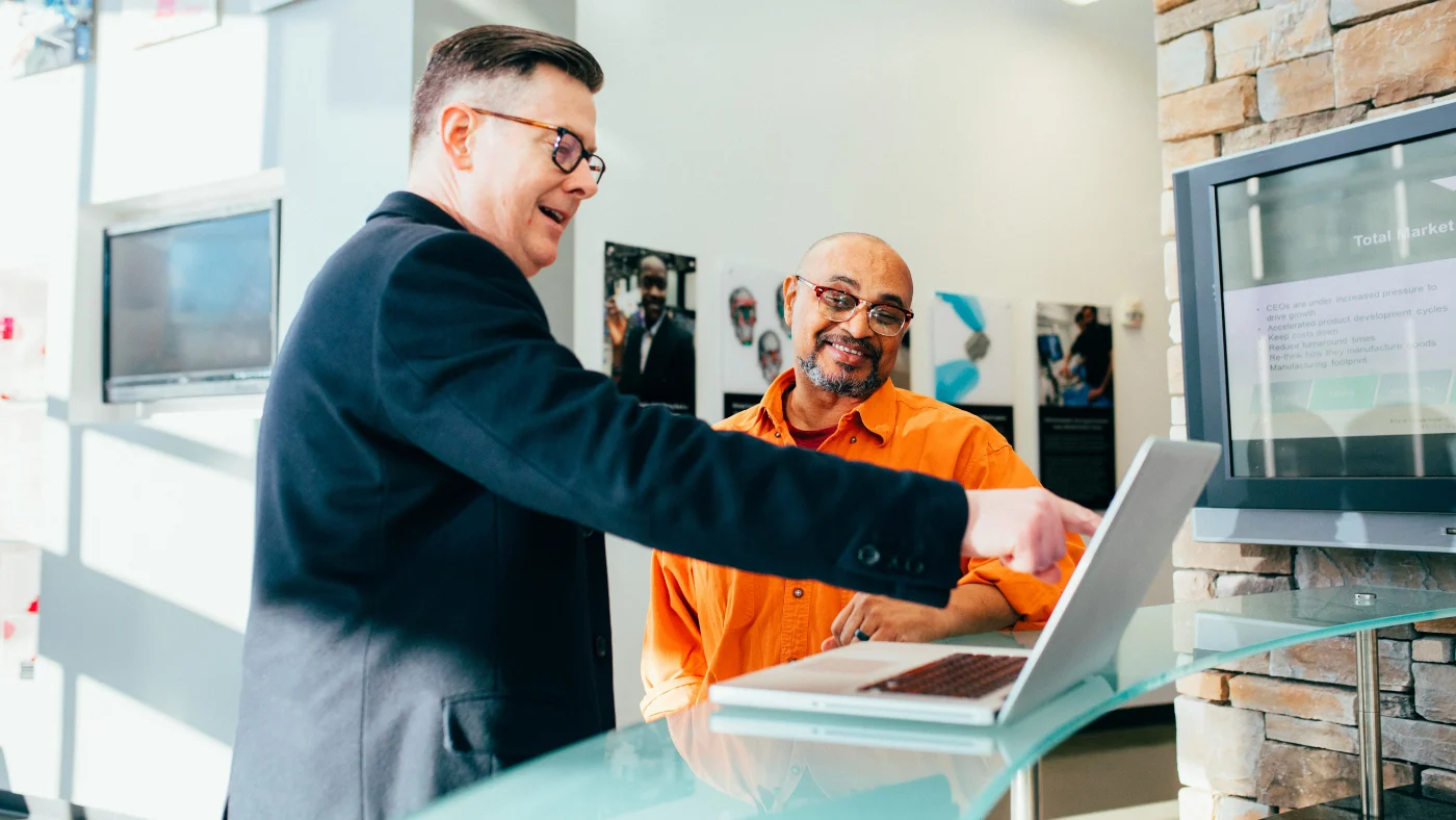 Two professionals reviewing information on a laptop, representing strong communication and great customer service in action