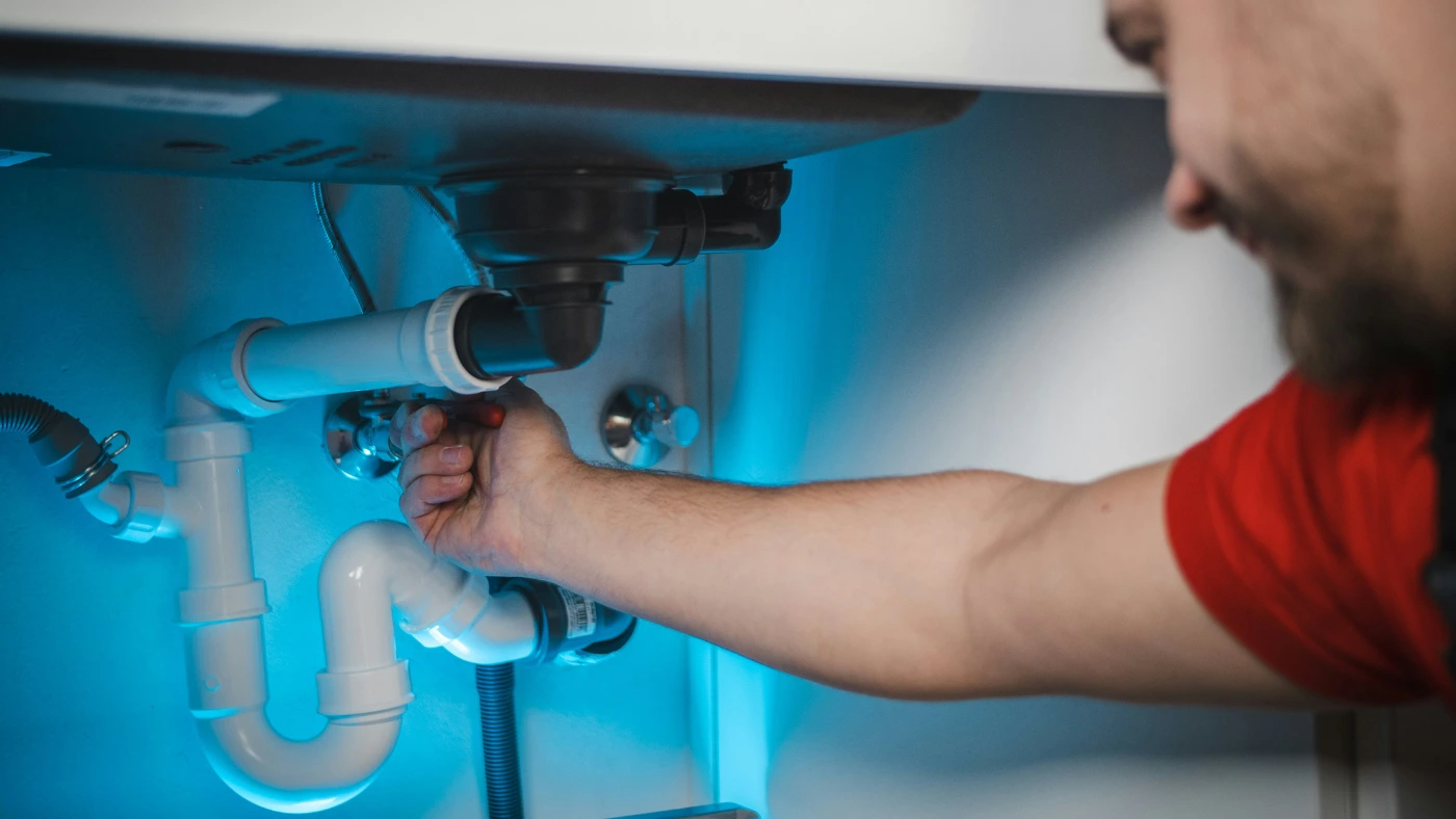 plumber working on a sink pipe