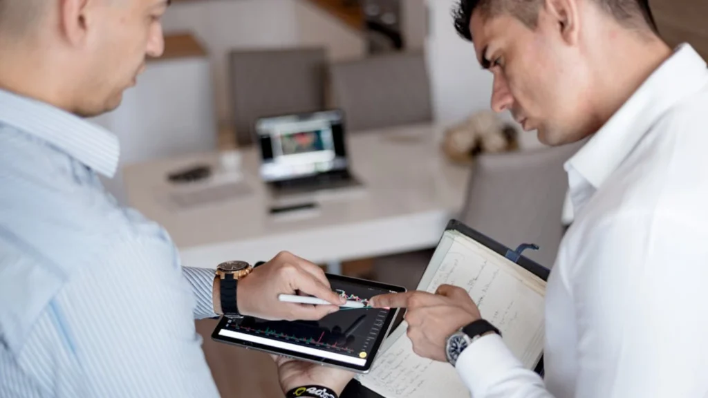 Two professionals reviewing performance data on a tablet during business discussion