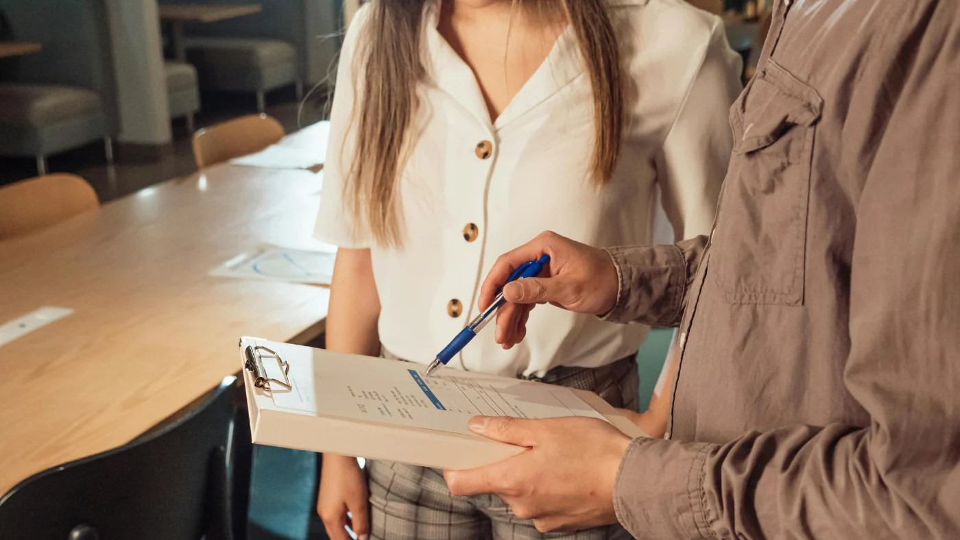 Two people standing and discussing documents