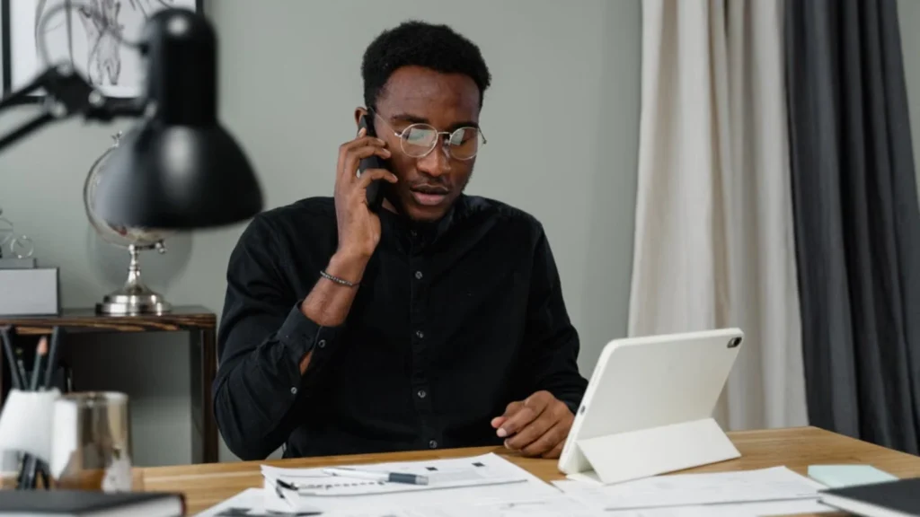 Home service business owner using AI prompts on phone and tablet at office desk