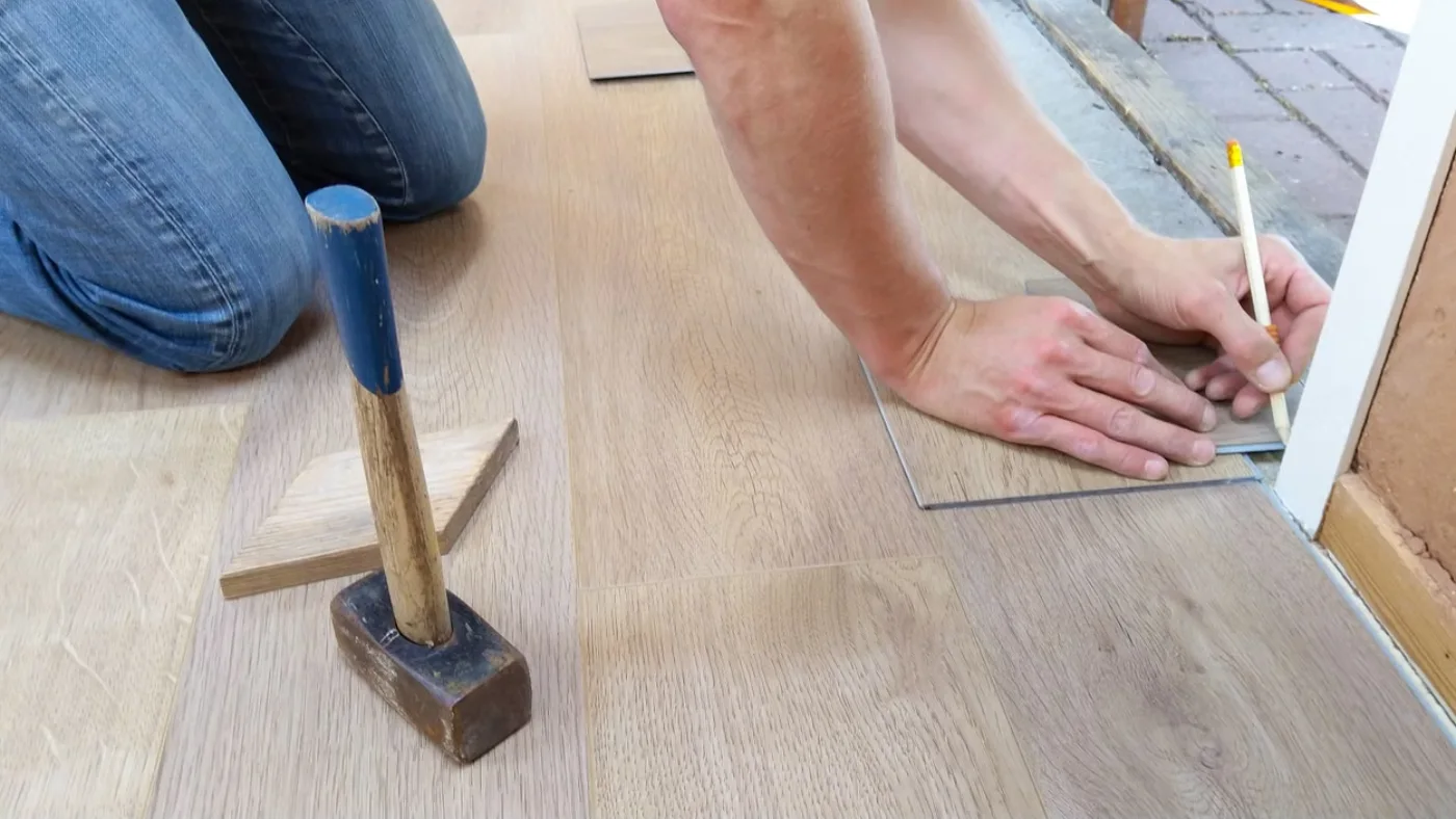 Flooring contractor measuring and cutting laminate flooring during installation to accurately price a flooring job.