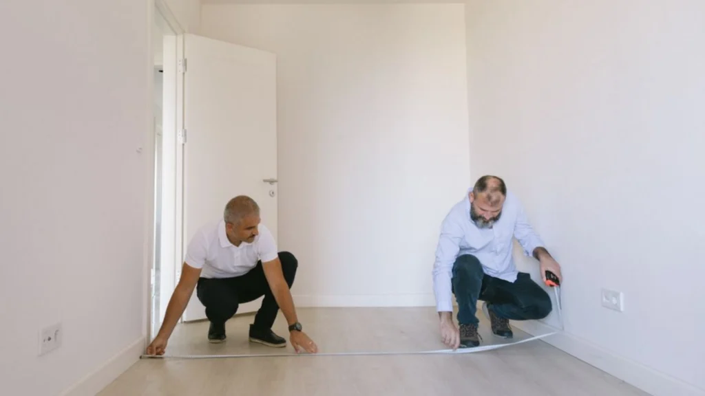 - Housecall Pro Flooring contractors measuring a room to calculate square footage, material requirements, and installation costs.