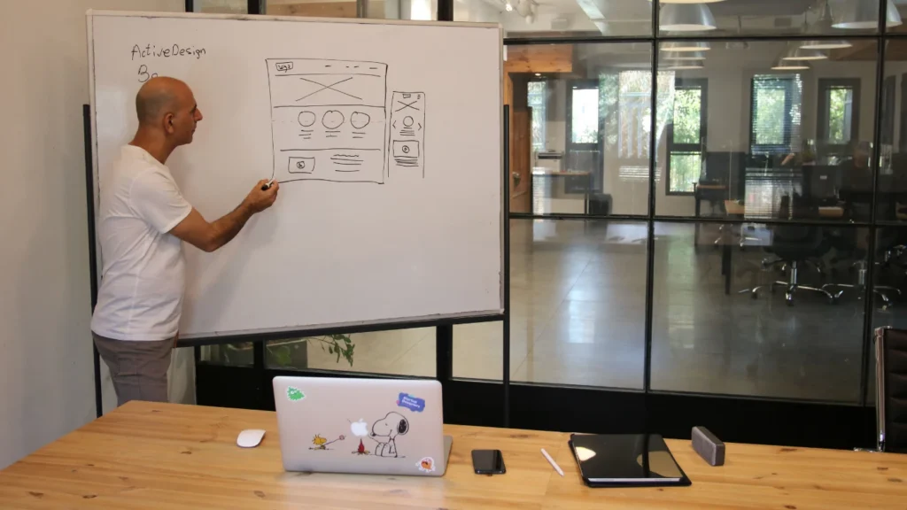 - Housecall Pro Professional designer in an office sketching a website layout on a whiteboard while explaining where to mention Klarna on a website