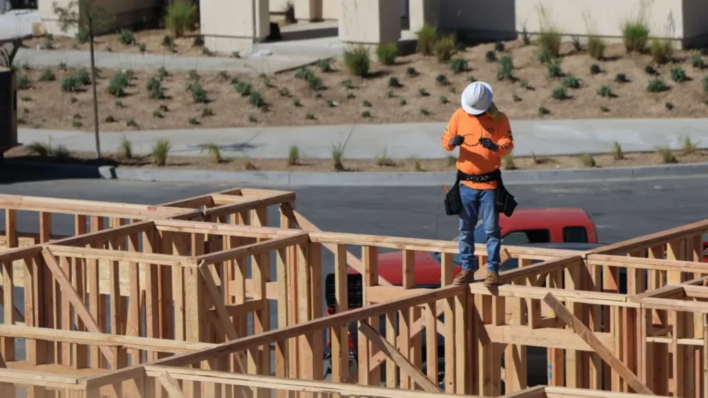 Construction contractor standing on the wooden frame of a new home.