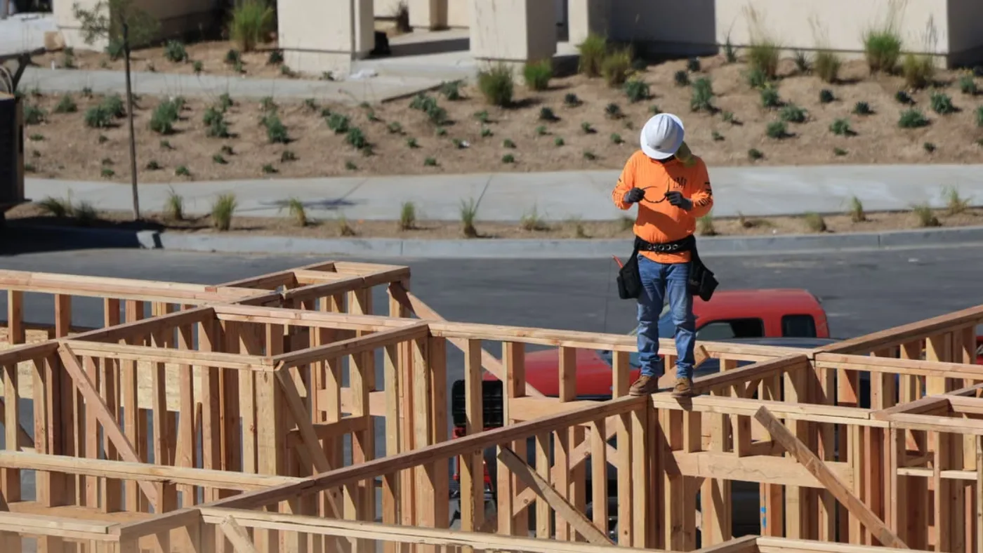 Construction contractor standing on the wooden frame of a new home.