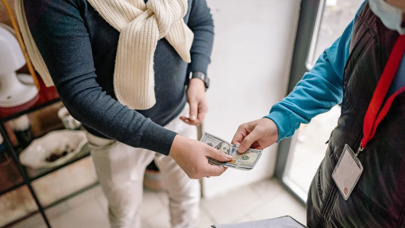 Customer paying a plumber in cash after completing a service job.